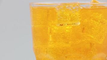 Rotieren Sie ein Glas Orangen-Mineralwasser-Getränk auf weißem Hintergrund. video