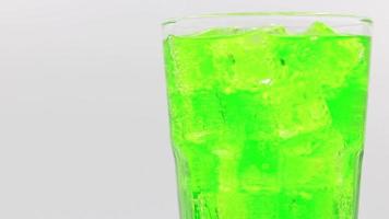 Green sparkling water with Ice in glass. Green sparkling water drink over white background. video