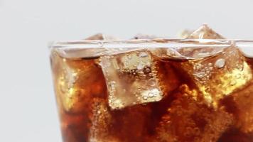 Cola with Ice in glass. Coke Soda closeup. Rotate glass of Cola drink over white background.