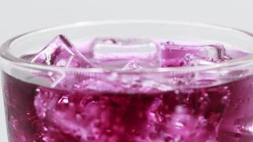 Rotate glass of Grape sparkling water drink over white background.