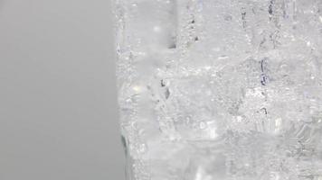 soda frizzante con ghiaccio in vetro. ruotare bicchiere di bibita acqua frizzante su sfondo bianco. video