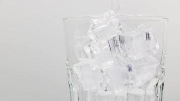 Soda Sprudelwasser mit Eiswürfeln aus nächster Nähe gießen. Soda Sprudelwasser mit Eis im Glas. drehen Glas Soda Mineralwasser trinken auf weißem Hintergrund. video