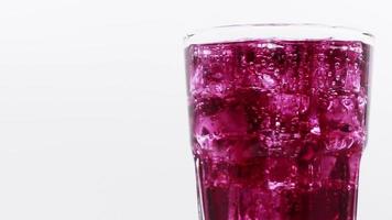 gire el vaso de bebida de agua con gas de uva sobre fondo blanco.
