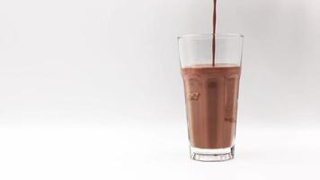 vierta la leche con sabor a chocolate en un vaso sobre un fondo blanco. video