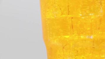 Rotate glass of Orange sparkling water drink over white background. video