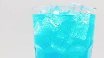 Rotate glass of Blue Hawaii sparkling water drink over white background. video