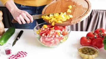 preparar alimentos saudáveis. mulher cozinhando salada de legumes. mãos femininas adicionando pimentão à tigela de salada
