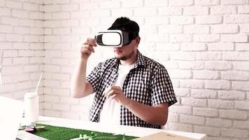Junger Mann, der eine virtuelle Realitätsbrille verwendet, um ein Dummy-Projekt für erneuerbare Energien zu erstellen video