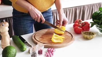 préparer des aliments sains. femme cuisinant une salade de légumes. mains féminines ajoutant des poivrons au saladier