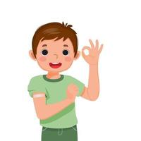 niño pequeño feliz mostrando parche pegado o yeso en su brazo después de recibir la inyección de la vacuna y haciendo gestos con el pulgar hacia arriba con expresión facial sonriente vector