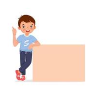 happy little boy leaning on empty poster or signboard showing thumb up gesture vector