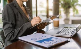 mano de mujer de negocios trabajando con una nueva computadora moderna y escribiendo en el diagrama de estrategia del bloc de notas como concepto foto