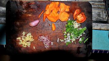 cortar verduras y hierbas en una tabla de cortar de madera tradicional foto