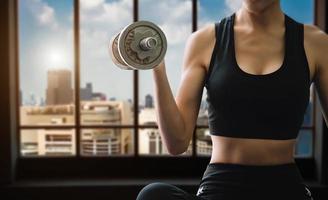 Determined woman losing weight at home and exercising with dumbbells. Sport and recreation concept. photo