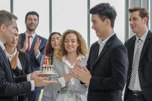 Multi ethnic diversity business people surprise birthday to asian male colleague with happy smiling faces, selective focus. photo