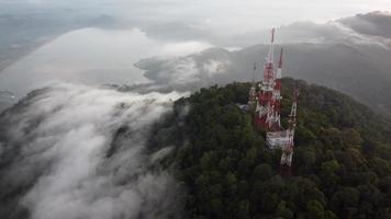 Four telecommunication at the top of hill with low cloud and beautiful lake video