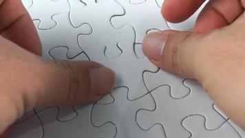 Male hand put the last white jigsaw puzzle. video
