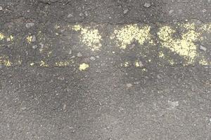 old road surface has yellow lines peeling off. photo