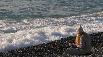 Frau liest eine Zeitung am Kiesstrand video