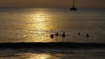 hermosa puesta de sol con siluetas de personas que disfrutan del océano. video