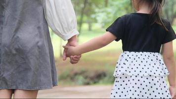 madre sosteniendo la mano de su hija en el jardín de primavera al aire libre. concepto de relación familiar video