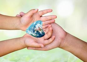 concept of saving the world. The heart of the world in the hands of children and mothers. photo