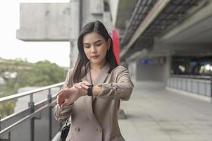 la mujer de negocios está usando un reloj inteligente en una ciudad moderna, tecnología de negocios, concepto de estilo de vida de la ciudad foto