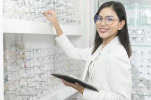 oftalmólogo joven que sostiene la tableta en el centro óptico, concepto de cuidado de los ojos. foto