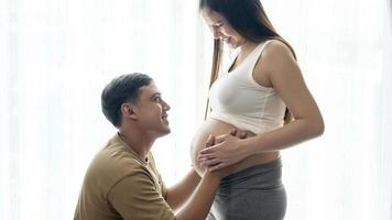Young pregnant woman with husband embracing and expecting a baby at home photo