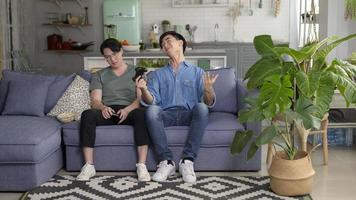 Young smiling gay couple playing video games in the living room at home, LGBTQ and diversity photo