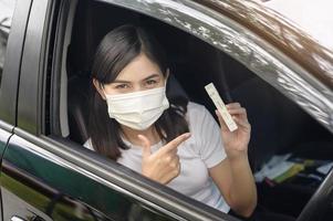 A woman holding atk in car, do a self-collection test for a COVID-19 test, health and safety photo