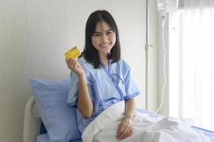 una joven paciente tiene una tarjeta de crédito, ingresa en el hospital, concepto de atención médica foto