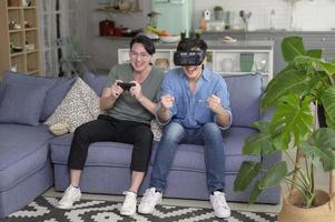 Young smiling gay couple playing video games in the living room at home, LGBTQ and diversity photo