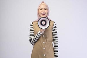 Happy muslim woman is announcing with megaphone on white background photo
