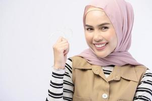 A young muslim woman holding invisalign braces in studio, dental healthcare and Orthodontic concept.. photo