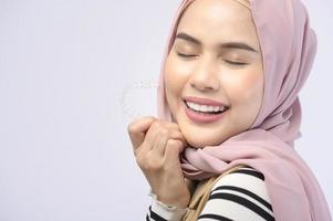 A young muslim woman holding invisalign braces in studio, dental healthcare and Orthodontic concept.. photo