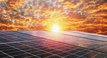 panel de células solares con cielo y puesta de sol. concepto de energía limpia en la naturaleza foto