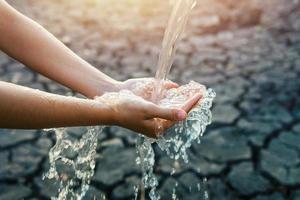 verter agua en la mano en el fondo de la luz de la mañana foto