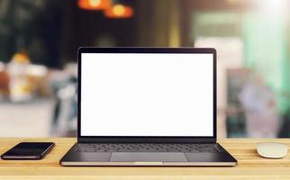 laptop computer blank white screen and mobile on table in cafe background photo