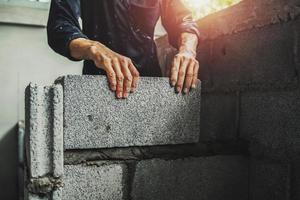Worker building wall bricks with cement photo