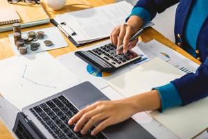 accounting concept. businesswoman working using calculator with money stack in office photo