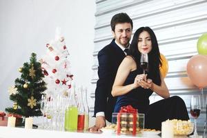 dulce pareja amor sonrisa y pasar romántico bebiendo vino en navidad y celebrando la víspera de año nuevo, día de san valentín con globos coloridos y cajas de regalo en el área de la despensa foto