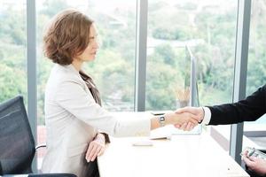 Successful businessman and businesswoman happy and shake hands after meeting for partnership in modern office photo