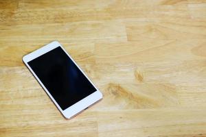 Smartphone with white screen on wooden table. photo