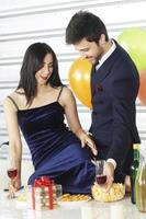 dulce pareja amor sonrisa y pasar romántico bebiendo vino en navidad y celebrando la víspera de año nuevo, día de san valentín con globos coloridos y cajas de regalo en el área de la despensa foto