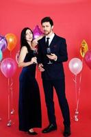 Sweet couple Love smile and spending Romantic with drinking wine in christmas time and celebrating new year eve, valentine day with colorful balloon on red background photo