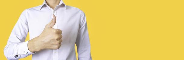 Businessman in white work clothes on a yellow background showing thumbs up to encourage work.Compliments for excellent work, encouragement for success. photo