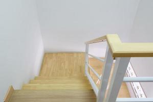 Modern curved wooden staircase with the white metal handrail. photo