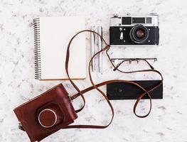 Flat lay, top view office table desk. Desk workspace with retro camera, diary, pen, glasses, case, cup of coffee on white background. photo