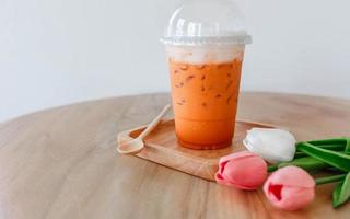 Iced Thai tea in plastic cup on wooden table photo